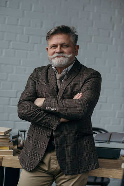 smiling senior writer leaning back on workplace