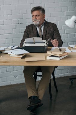 handsome senior writer in tweed suit working with typewriter clipart