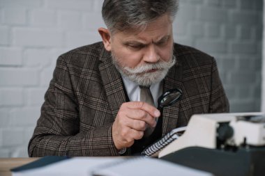 bearded senior writer reading manuscript with magnifying glass clipart