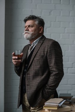 senior man in tweed suit with glass of whiskey looking away clipart