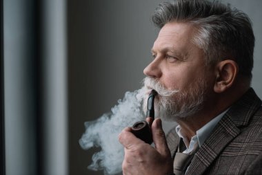 bearded senior man in tweed costume smoking pipe clipart