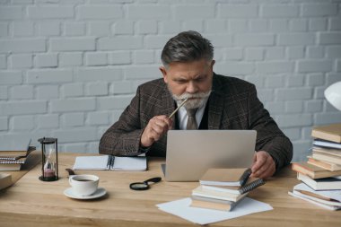 düşünceli kıdemli yazar laptop ile çalışma