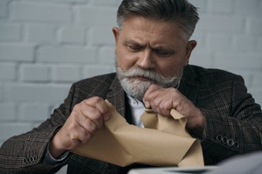 close-up portrait of disappointed senior writer tearing his manuscript clipart