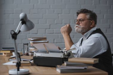İşyerinde oturan ve uzağa bakarak düşünceli kıdemli yazar