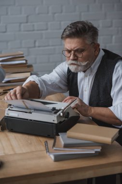 ciddi gri saçlı yazar vintage daktilo kağıt yükleme
