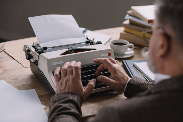 close-up shot of senior writer working with typewriter