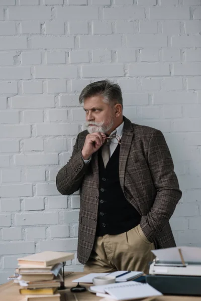 handsome senior writer in tweed suit standing near workplace