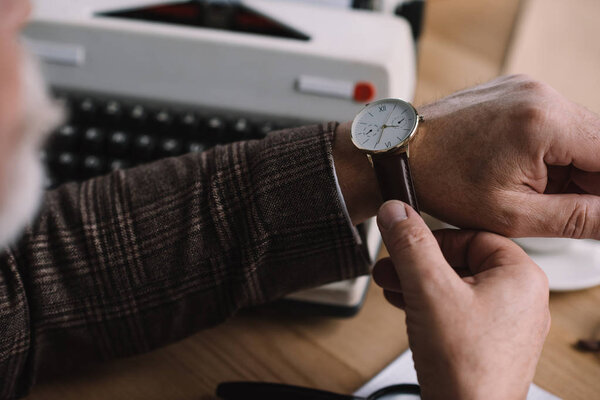 cropped shot of senior writer putting on his vintage watch