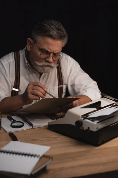 Fokussierte Senior Writer Arbeit Mit Manuskript Isoliert Auf Schwarz — Stockfoto