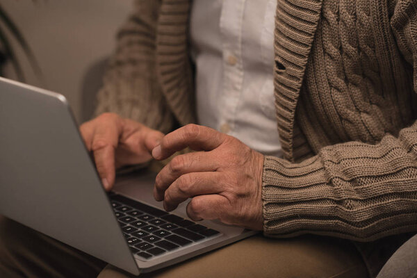 cropped shot of senior man using laptop