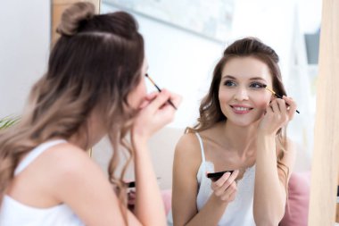 aynaya bakarak ve makyaj uygulamak güzel gülümseyen kız 