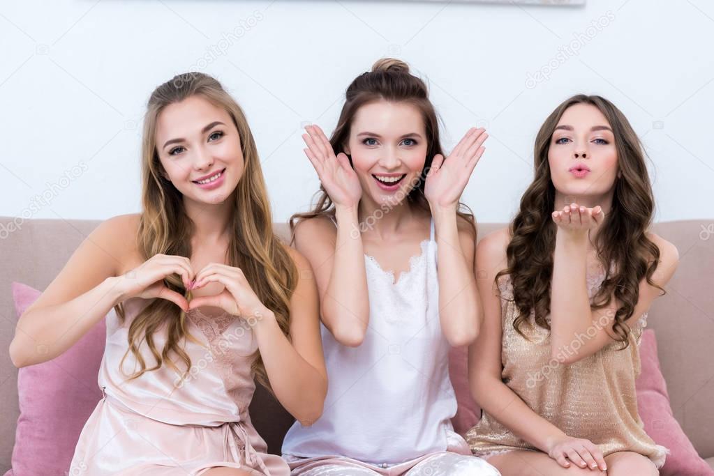 beautiful young women in pajamas gesturing with hands and smiling at camera