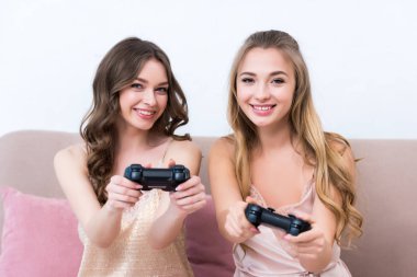 joystick ile oynama ve kameraya gülümseyen pijama güzel mutlu kızlar