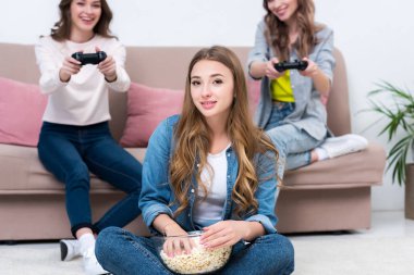 cam kase patlamış mısır yemek ve kamera joystick ile oynarken arkadaşlar süre bakarak genç kadın