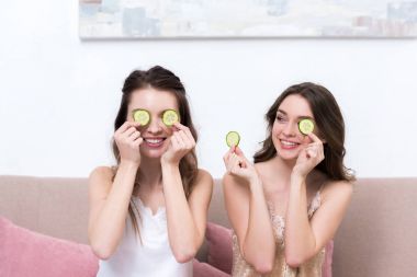 gözleri yakınındaki salatalık dilimleri tutan pijama gülümseyen güzel kızlar