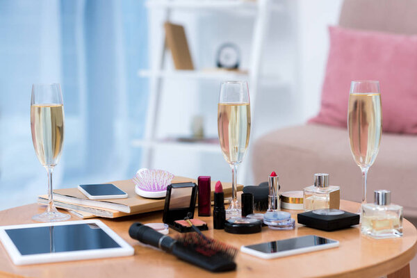 close-up view of digital devices, glasses of champagne and various cosmetics on table   