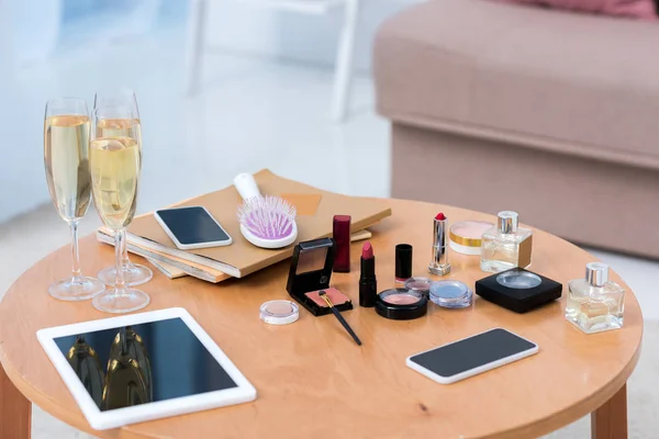 close-up view of digital devices, glasses of champagne and cosmetics on table