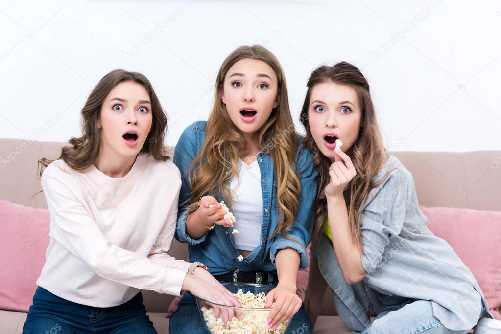 shocked young woman eating popcorn and watching movie together