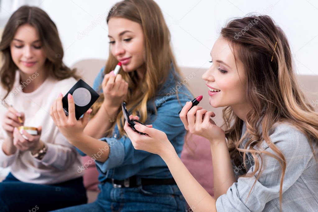 attractive smiling young women applying makeup together at home 