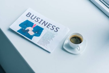 fincan kahve ve iş gazete bakış beyaz yüzey üzerinde kapatın