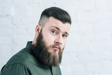 portrait of handsome bearded man in shirt against white brick wall clipart