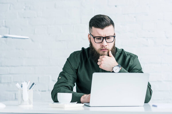 portrait of focused businessman working on laptop at workplace