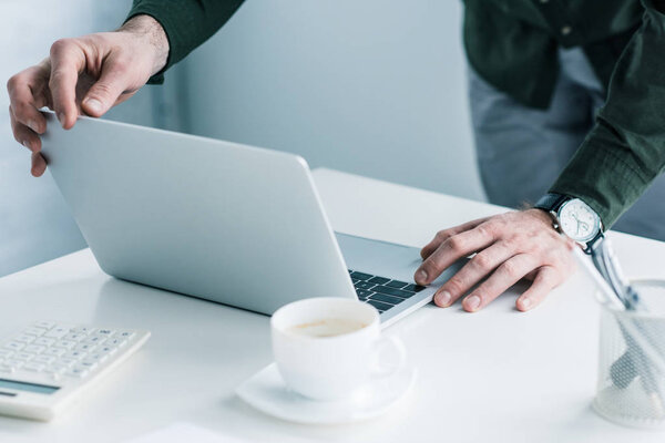 cropped shot of businessman working on laptop at workplace