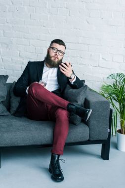 el koltukta istirahat smartphone ile takım elbiseli sakallı işadamı