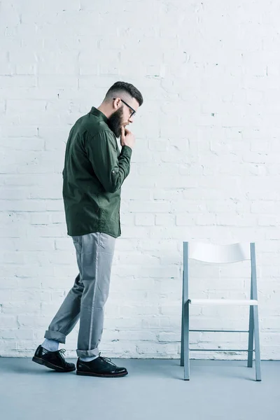 Side View Thoughtful Businessman Eyeglasses Standing Chair White Brick Wall — Stock Photo, Image