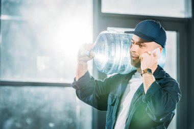Su şişesi taşıyan ve telefonda konuşurken kurye