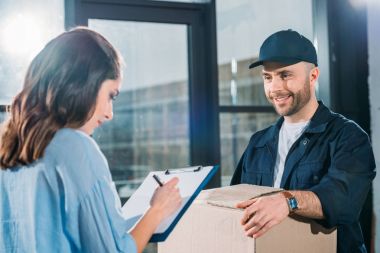 Woman sighing cargo declaration while courier holding box