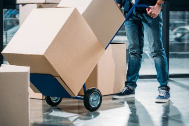 Close-up view of delivery man carrying boxes on cart clipart