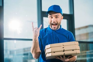 Excited courier with pizzas in boxes showing rock sign clipart
