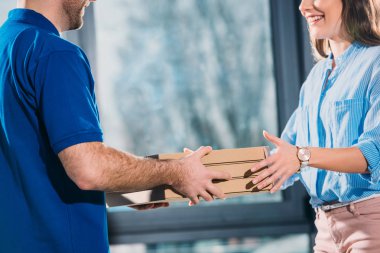 Woman receiving pizzas in boxes from delivery man  clipart