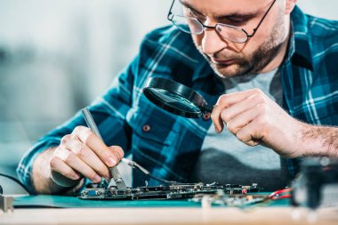 Engineer fixing circuit board looking through magnifying glass clipart