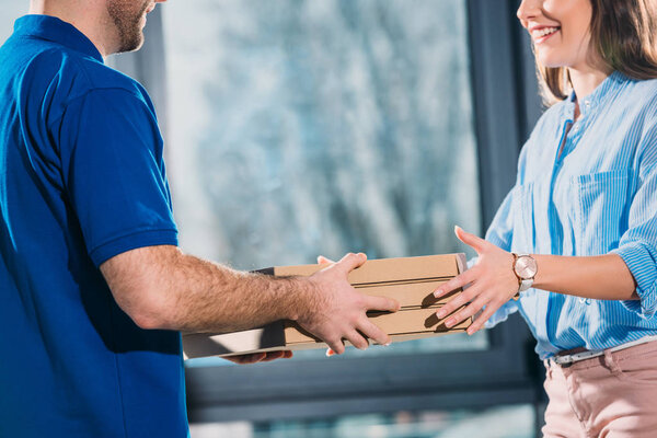 Woman receiving pizzas in boxes from delivery man 
