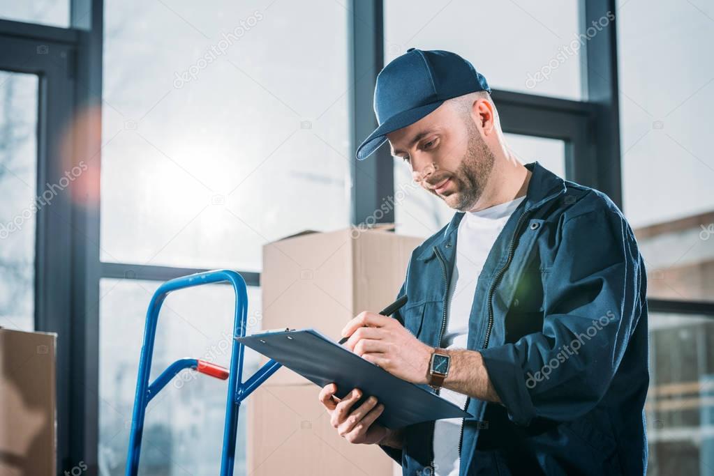 Loader man filling cargo declaration by stacks boxes