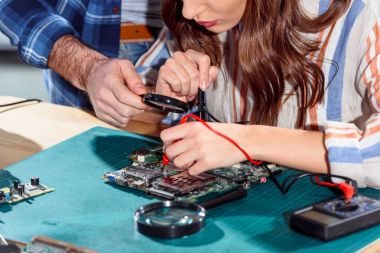 Man helping woman testing elements of circuit board clipart