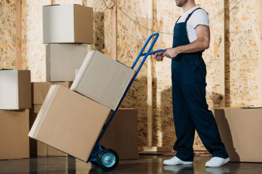 Delivery man carrying boxes on hand truck clipart