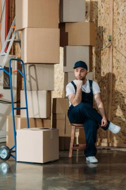 Resting delivery man sitting by stacks of boxes clipart