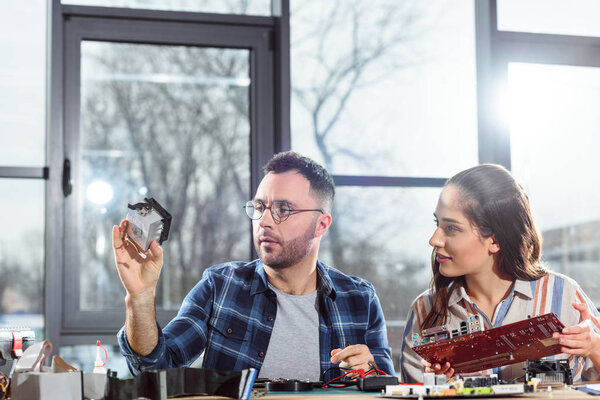 Woman and man engineers looking at hardware element