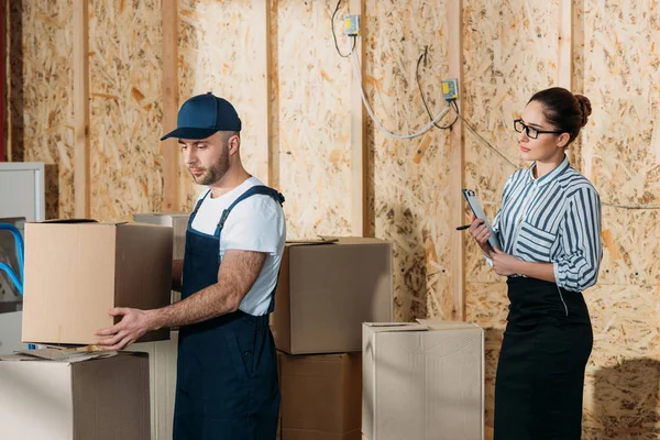Businesswoman Looking Delivery Man Stacking Boxes — Free Stock Photo