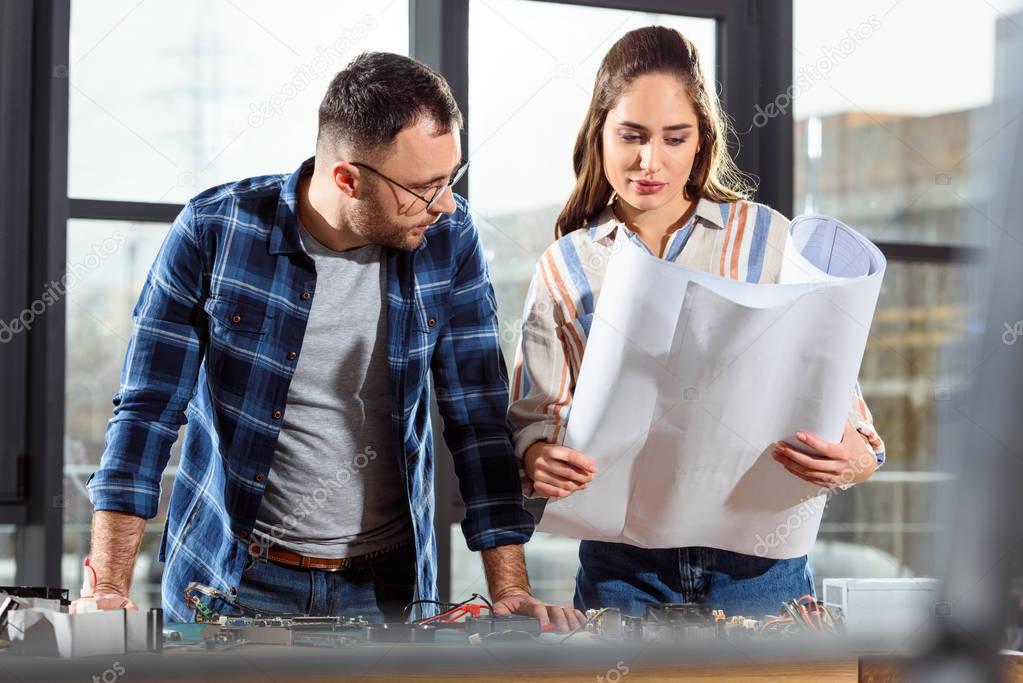 Woman showing project blueprint to male engineer