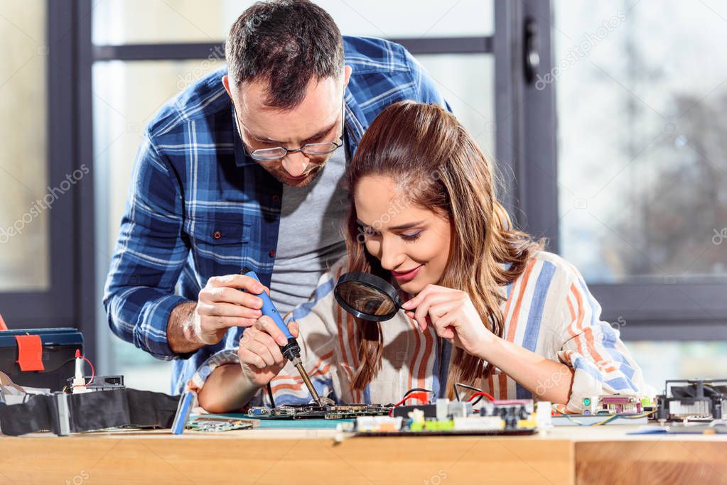Female and male engineers soldering circuit board