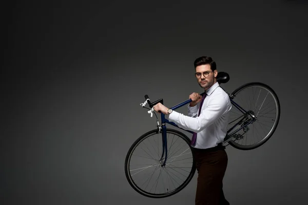 Joven Hombre Negocios Gafas Sosteniendo Bicicleta Manos Aisladas Gris —  Fotos de Stock