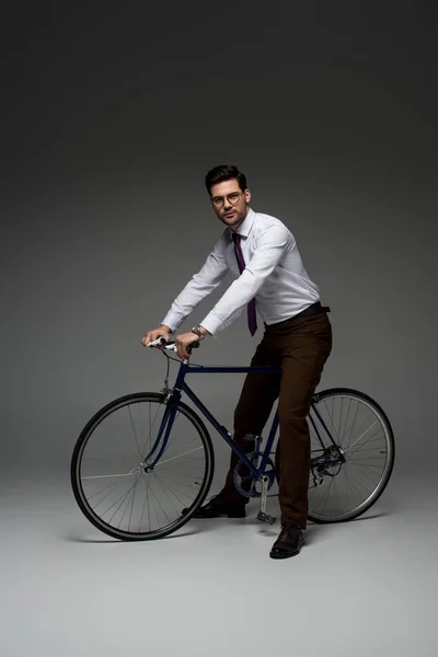 Stilvoller Geschäftsmann Mit Brille Sitzt Auf Fahrrad Auf Grau — Stockfoto