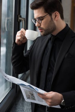 Kahve içme ve gazete tutan işadamı 