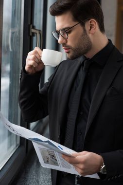 Businessman drinking coffee and holding newspaper  clipart