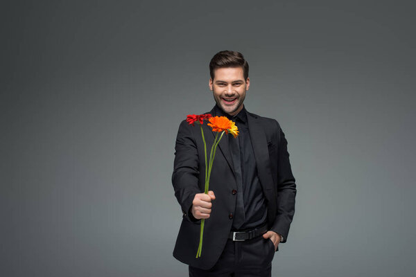 Young man with bouquet of flowers isolated on grey, international womens day concept