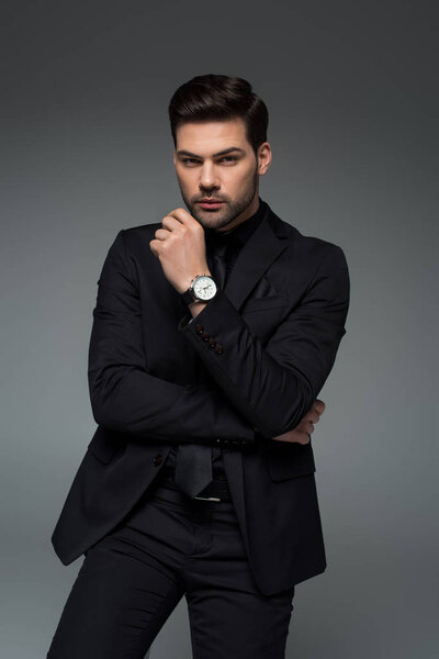 Stylish young man in formal suit posing isolated on grey